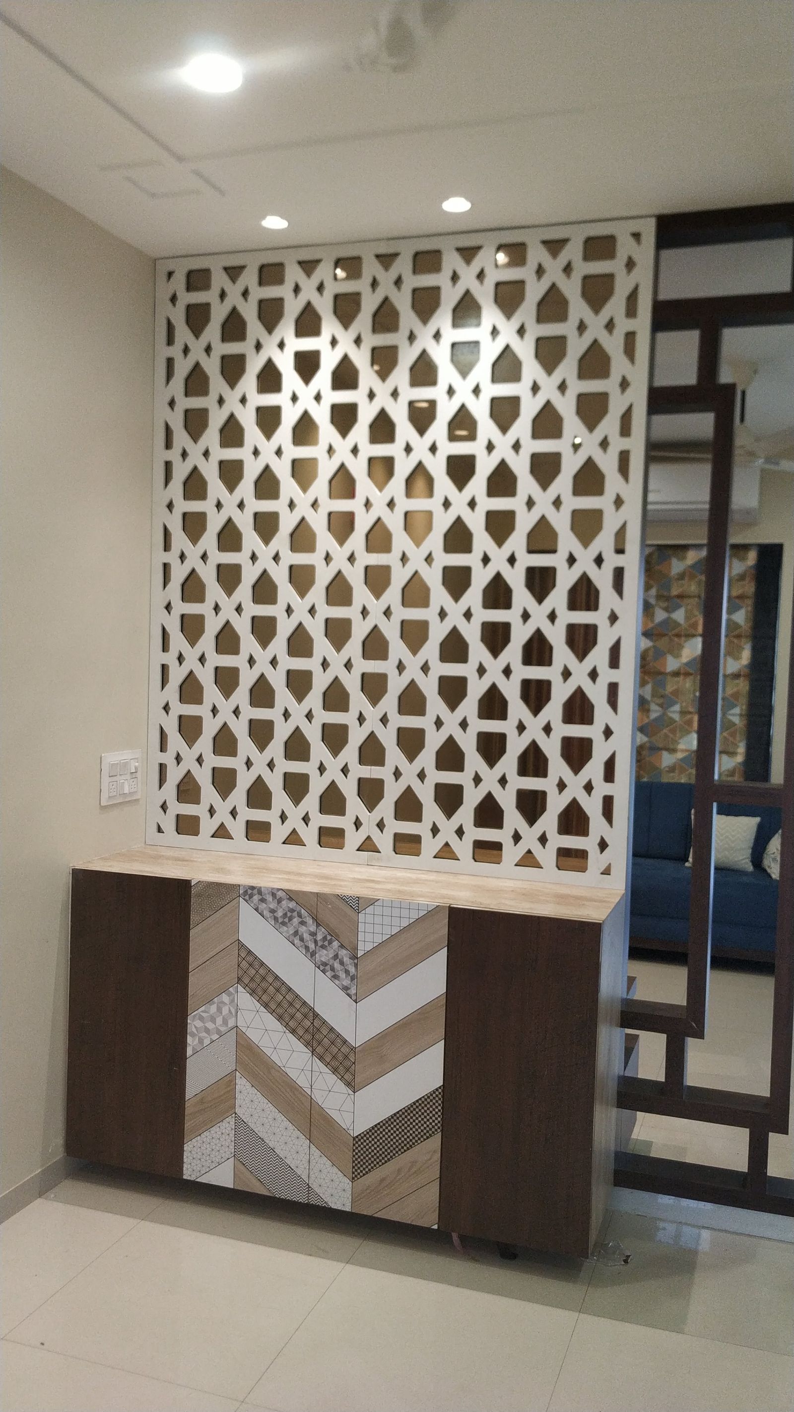 Foyer jaali partition wall above a chevron-pattern console unit