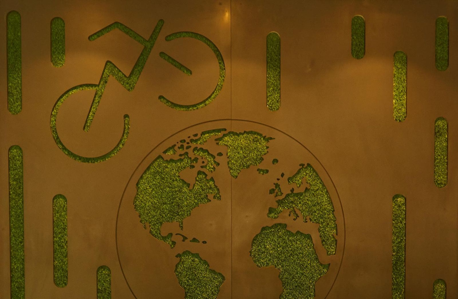Laser-cut sustainability motif detail: a globe and bicycle in moss